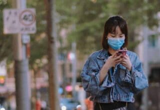 Woman in mask using smartphone